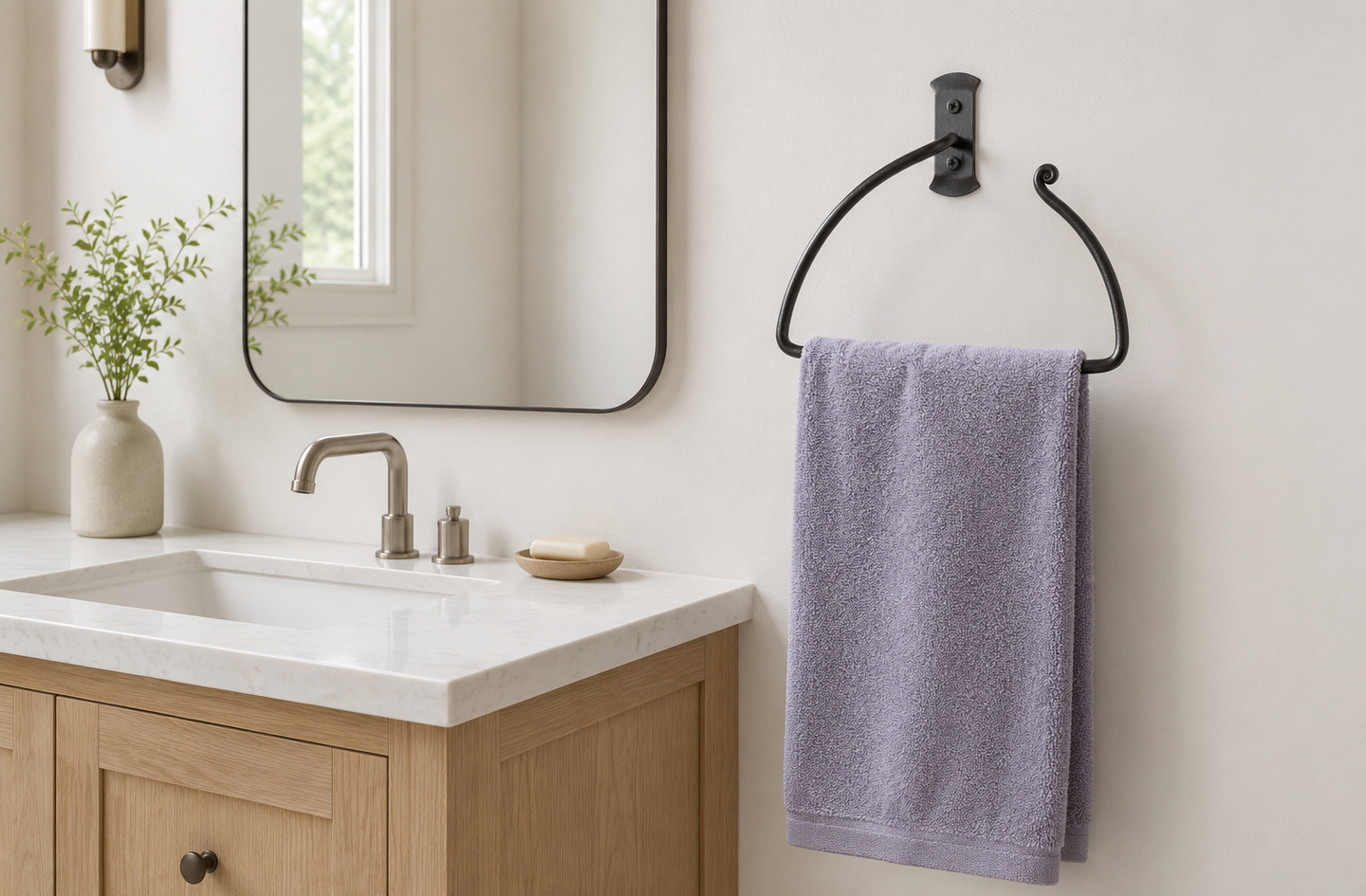 An RTZEN wrought iron half-circle hand towel ring mounted on a white bathroom wall at the standard height of hand towel ring placement, beside a light wood vanity with a marble countertop and a modern metal faucet.