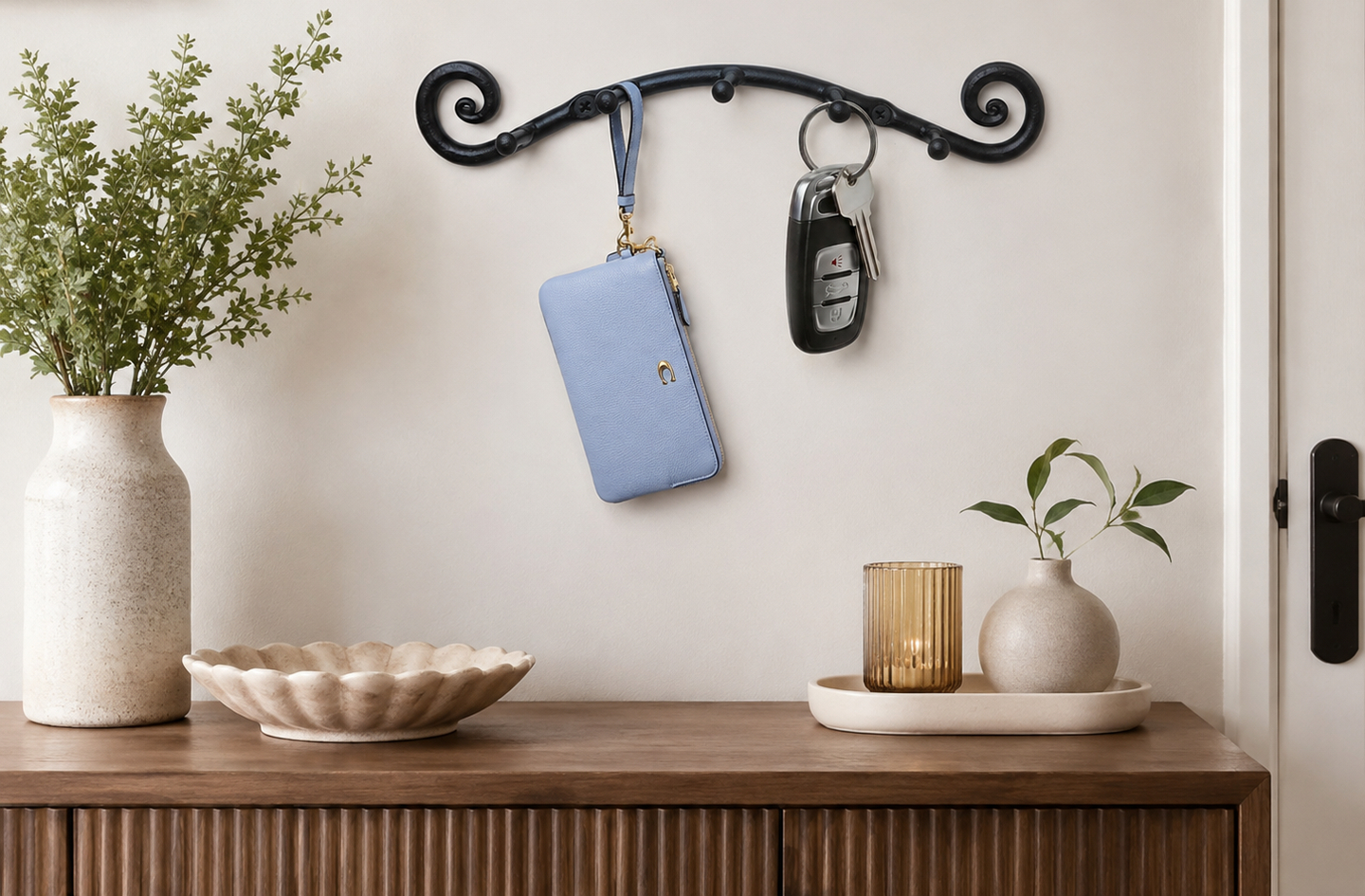 Where to hang key holder on wall: black wrought iron swirly key holder mounted above a wooden console table in an entryway