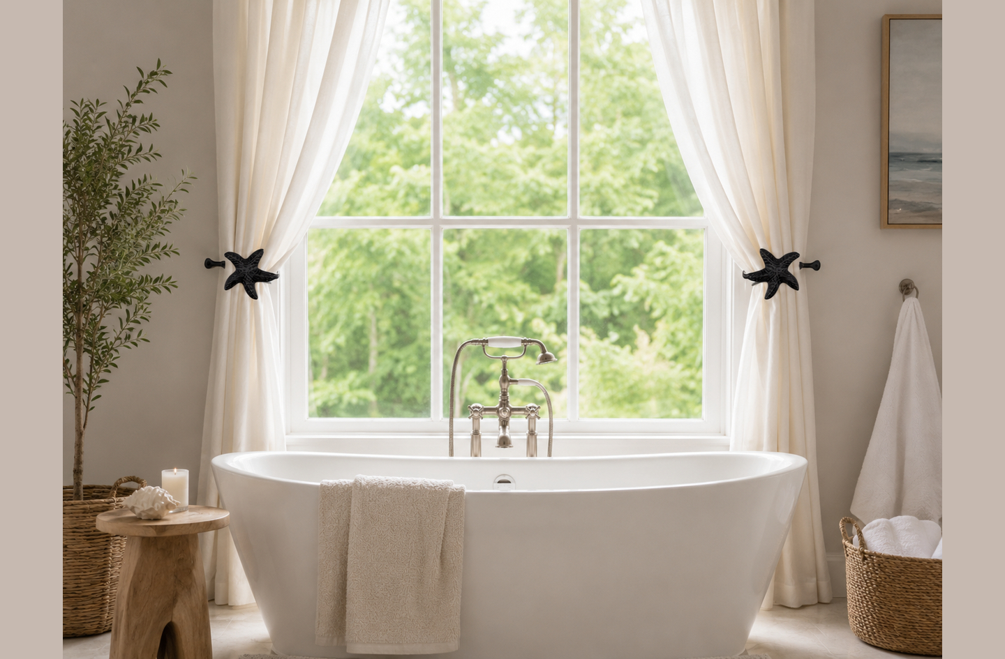 A pair of black wrought iron starfish curtain holdbacks keeping white curtains tied back around a window above a white freestanding bathtub